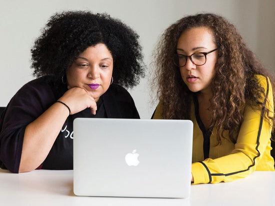 Two women looking at a macbook screen